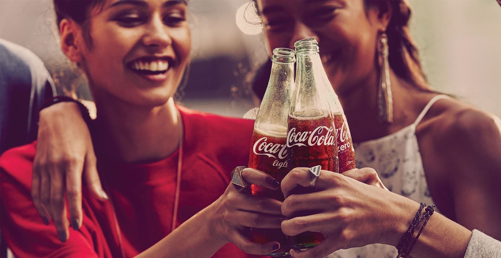 O que é branding: Foto de algumas pessoas sorrindo e brindando com garrafas de Coca Cola na mão.